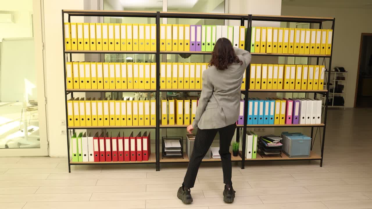 Woman Dancing in Office with Shelves of Folders