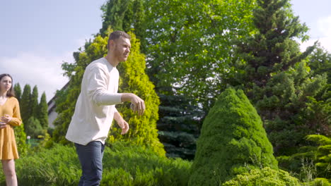 bottom view of caucasian young man throwing a petanque ball in the park on a sunny day while his friends waiting their turns