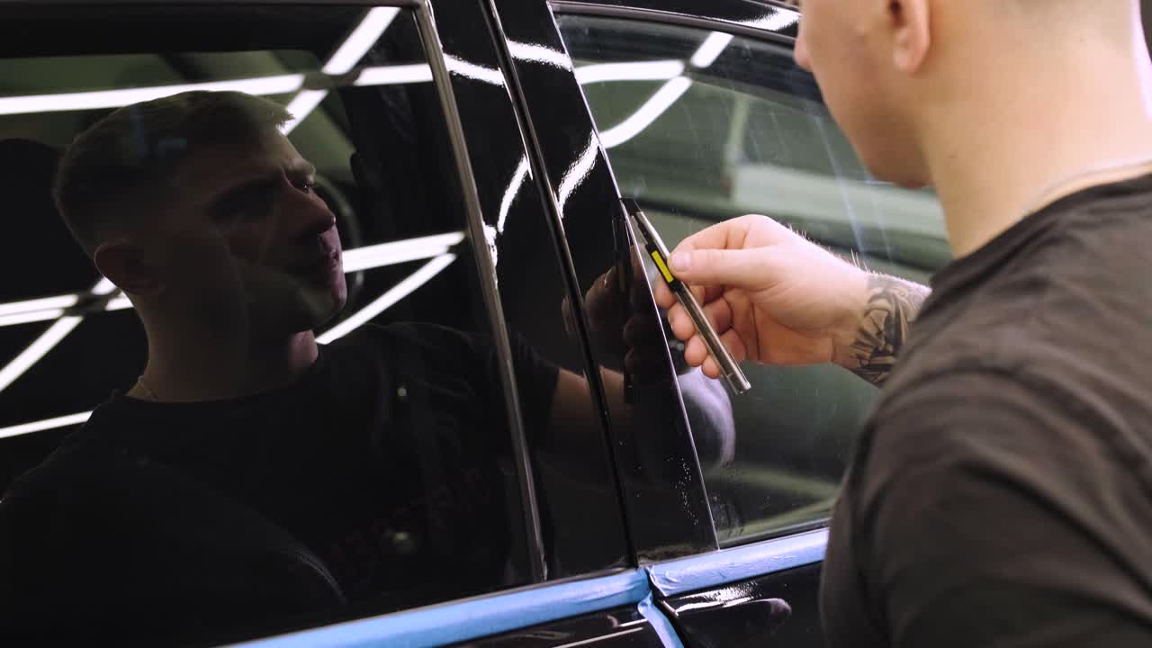 hombre que cubre el coche con cinta de poliuretano de vinilo. películas para el coche. pegatina película protectora en el coche