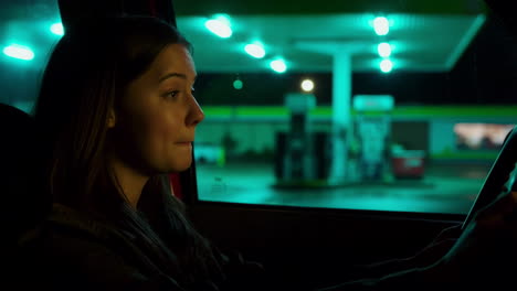 woman in car at gas station at night