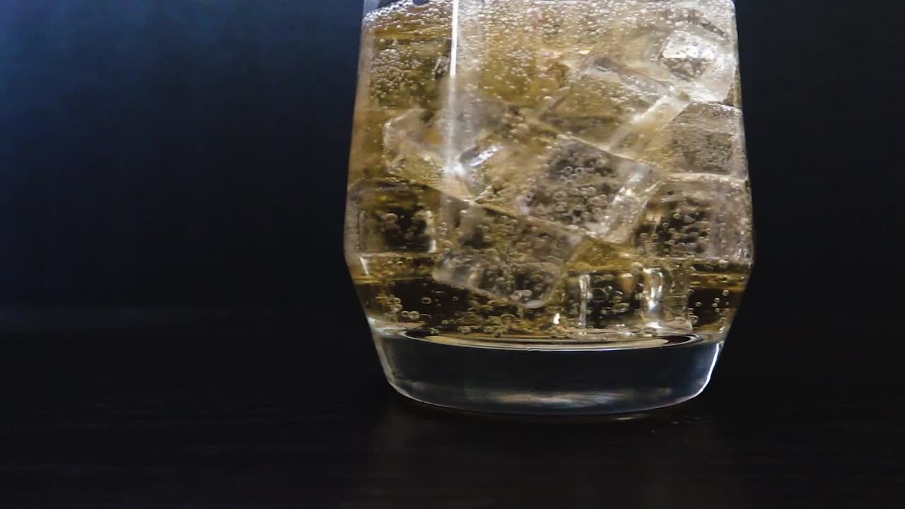 primer plano de hielo que cae en soda espumosa
