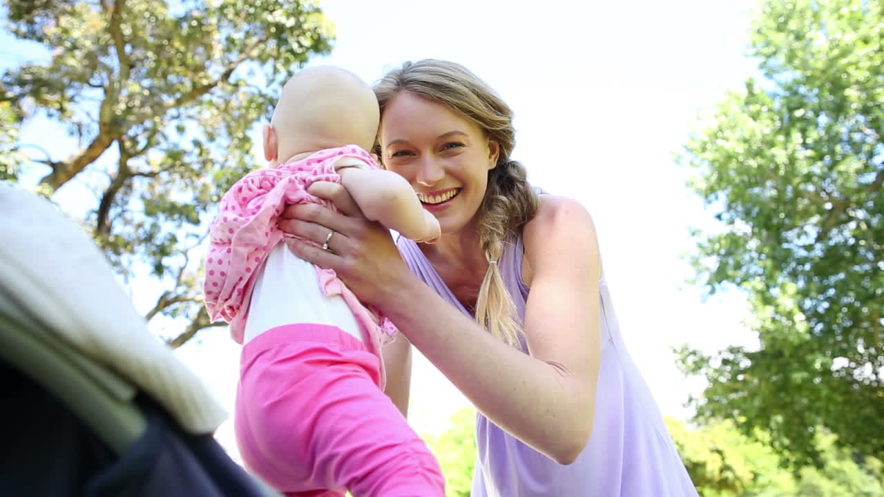 Mutter kümmert sich im Park um ihr Baby im Kinderwagen.