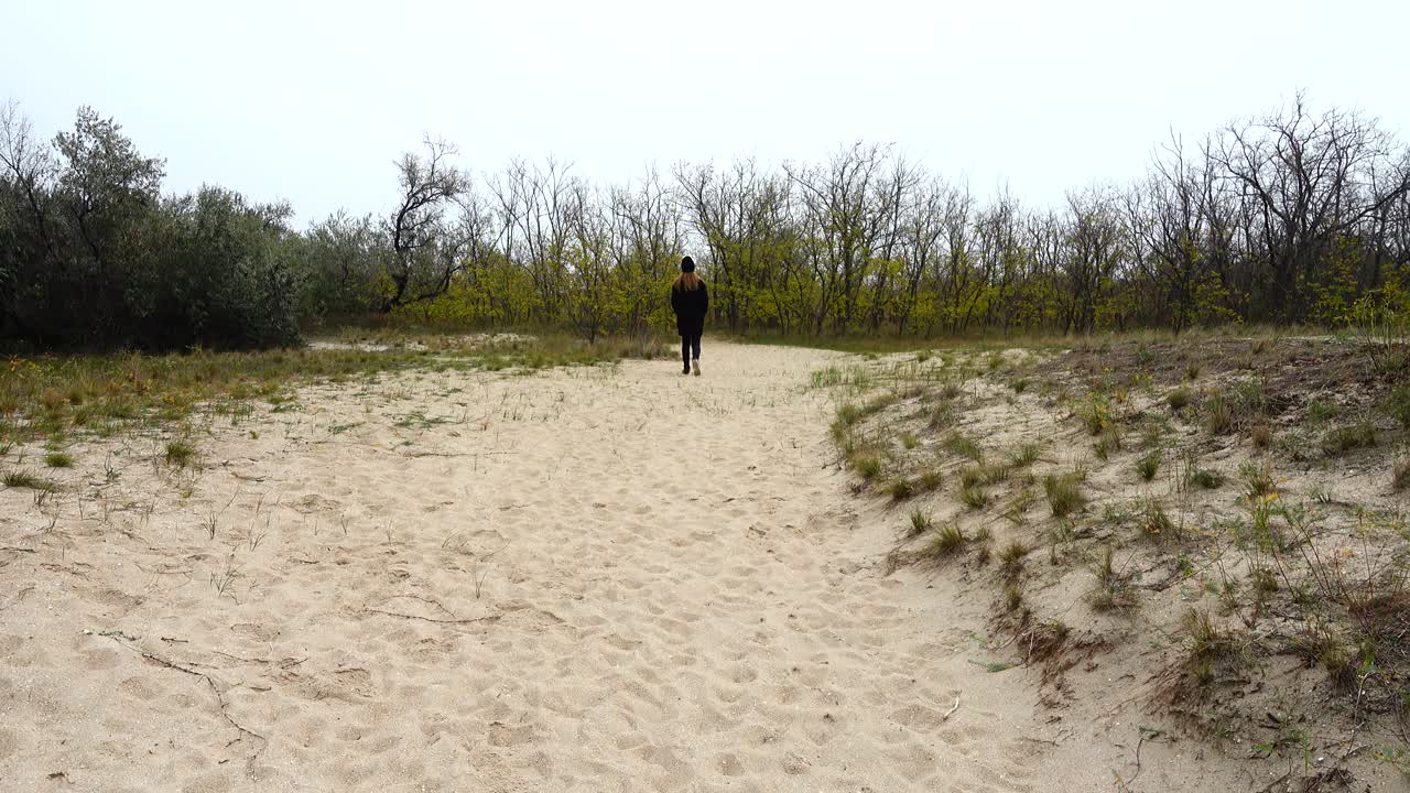 The girl goes on a footpath. Shooting in the fall