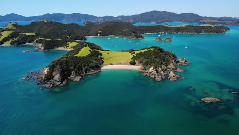 Picturesque-sandy-beach-surrounded-by-cliffs-and-lush-green-hills-aerial