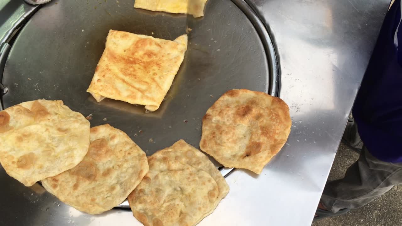 cocinar panqueques tailandeses exóticos, roti malaysian con diferentes rellenos en un mercado de tailandia. hacer rollo de roti de huevos en sartenes de metal calientes con aceite hervido. comida callejera de tailàndia. postre tailandés.