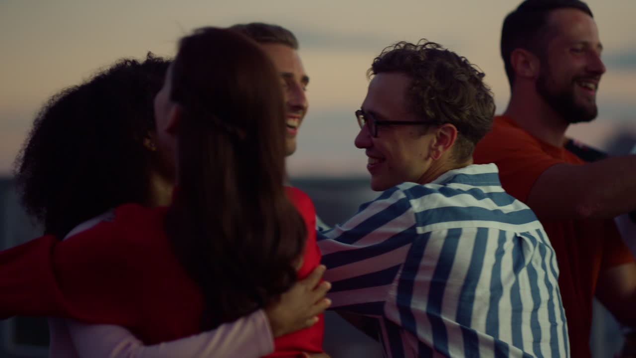 gente alegre abrazándose en una fiesta nocturna, amigos saludándose al aire libre.