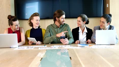 un equipo de negocios sonriente interactuando entre sí en la sala de conferencias