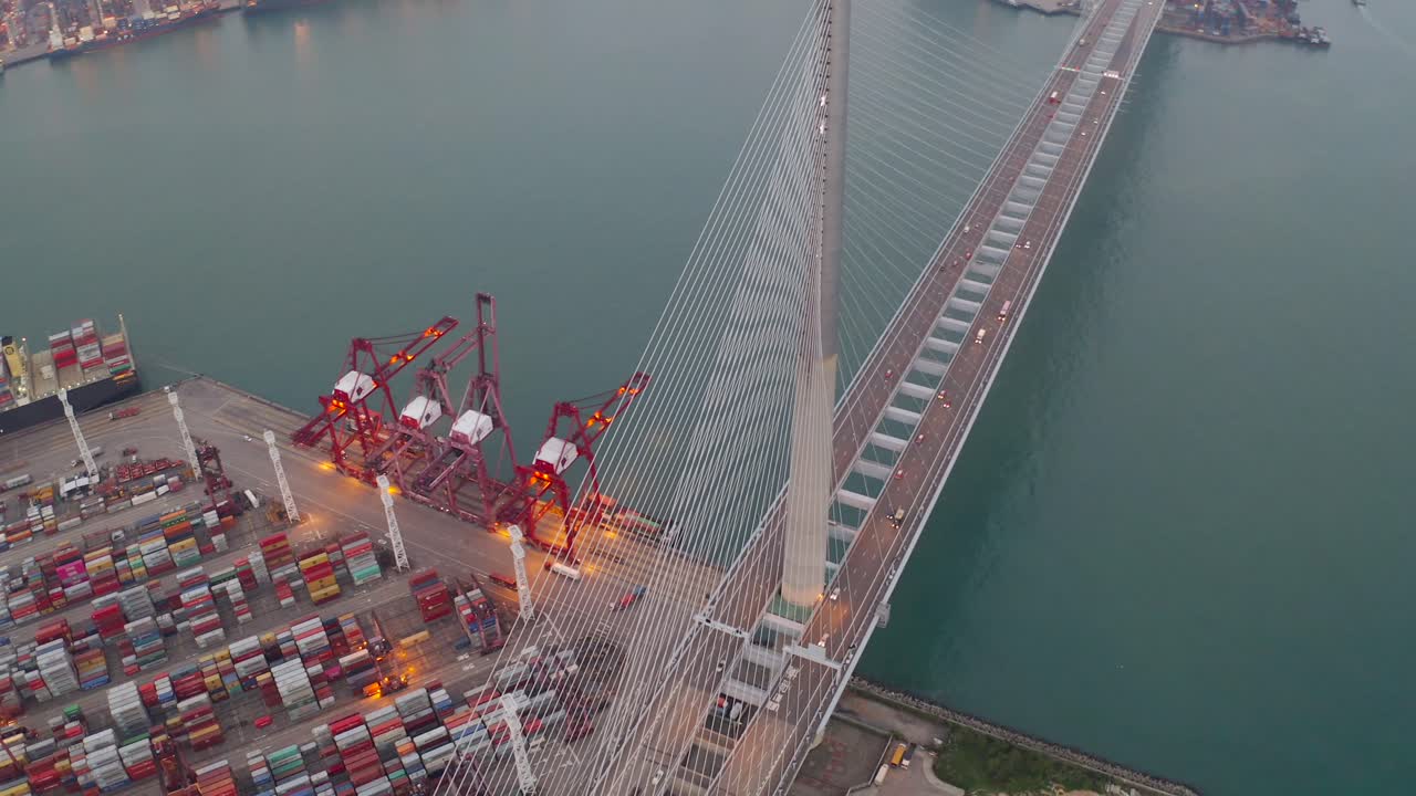 High-angle footage of a bustling shipping port featuring rows of organized cargo containers and towering cranes used for maritime logistics. Adjacent to the port