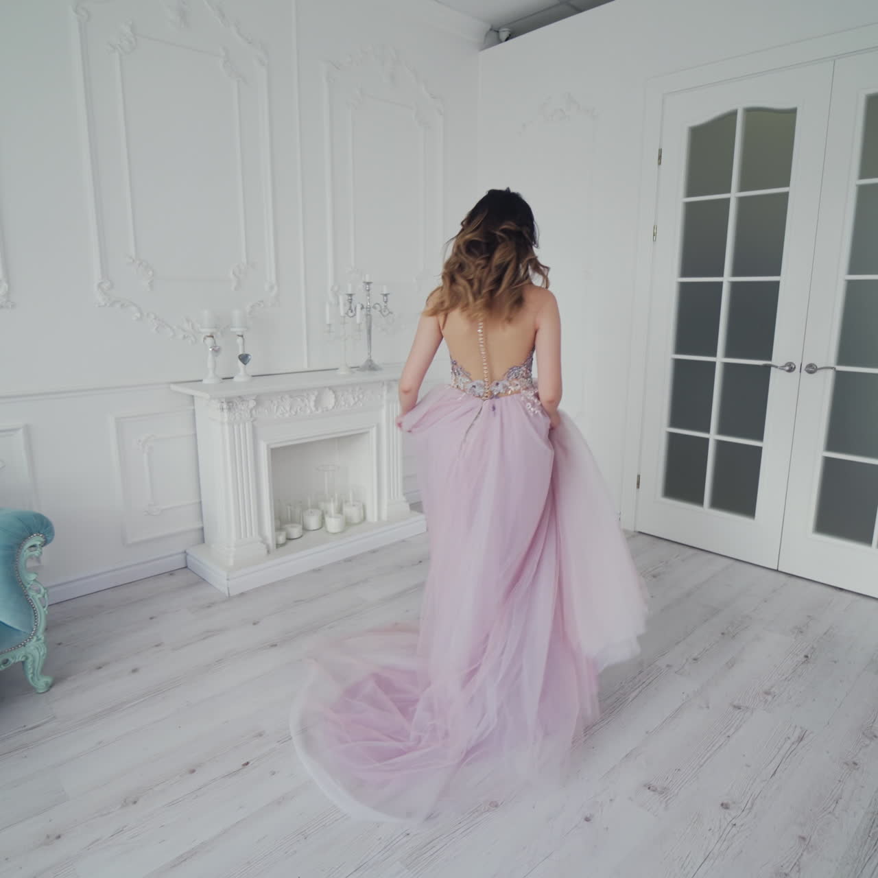 Young model in wedding dress is spinning happily in a spacious room. Romantic bride is posing in a hotel room in her wedding dress.