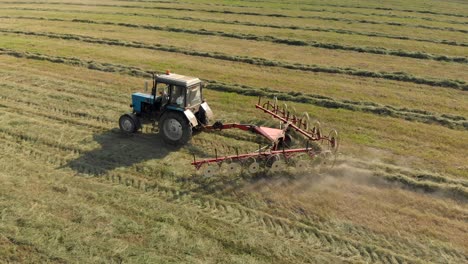 aerial view of a farmer on a tractor raking dry hay in the field with a rake-trowel