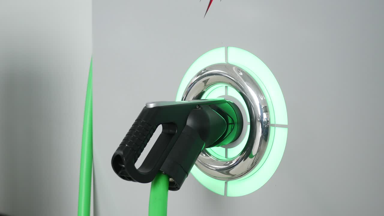 primer plano de una estación de carga de vehículos eléctricos con un cable verde conectado