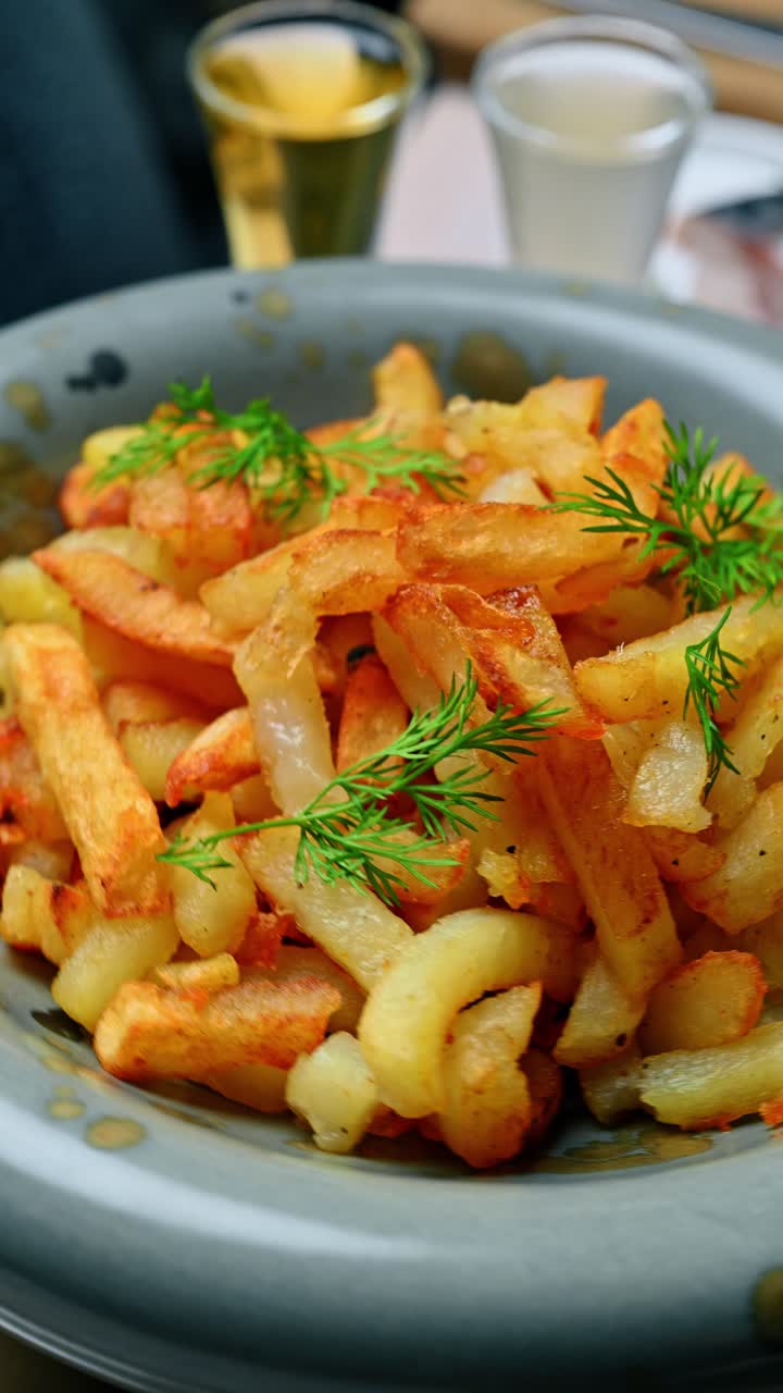 Traditional fried potatoes in ceramic bowl with herbs. Macro shot of golden fried potatoes seasoned with dill served in a rustic ceramic bowl on a table