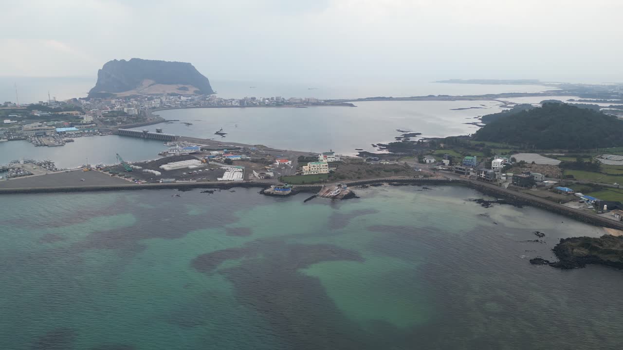 Drone aerial view in South Korea countryside flying over the ocean with a big green crater at sunrise small village island jeju island panning
