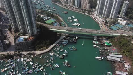 aerial view of aberdeen typhoon shelter, hong kong, with tilt up to full view of city skyline and thousands of boats.