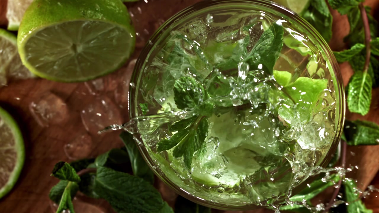 Hidastettu jääpala roiskahtamassa virkistävään Mojito-cocktailiin