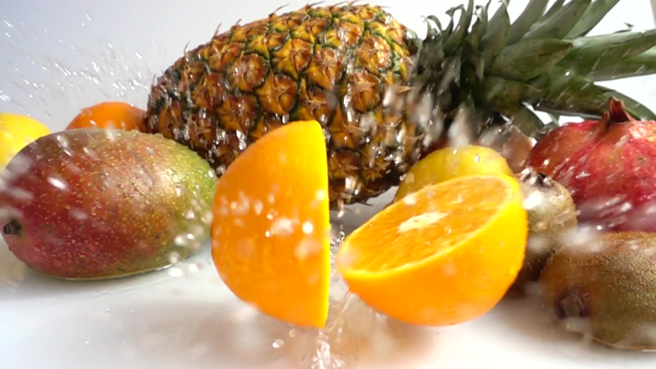 Caída de naranja sobre un fondo de frutas tropicales. Cámara lenta.