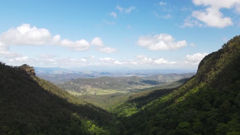 clouds casting shadows over a lush green valley leading to distant mountain ridge