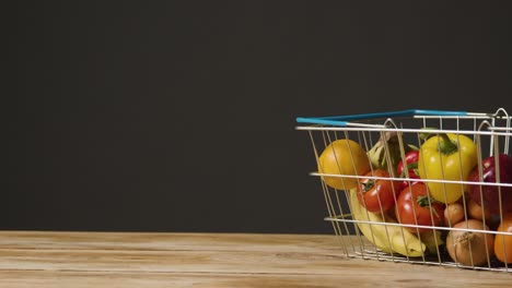 studio shot of basic fresh fruit and vegetable food items in supermarket wire shopping basket