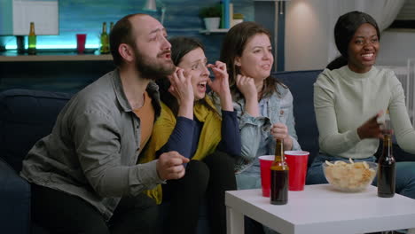 group of mixed people watching sport on television at home