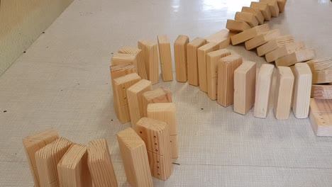 Snake-shape-wooden-domino-pieces-falling-in-to-each-other-on-table