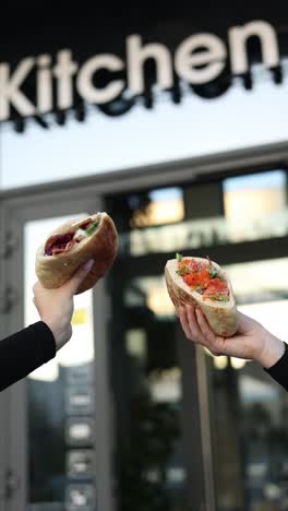 two pita sandwiches held up