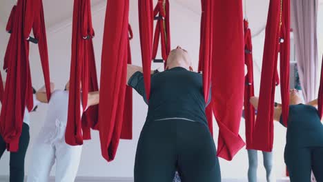 group-puts-hands-behind-head-relaxes-in-fly-yoga-hammocks