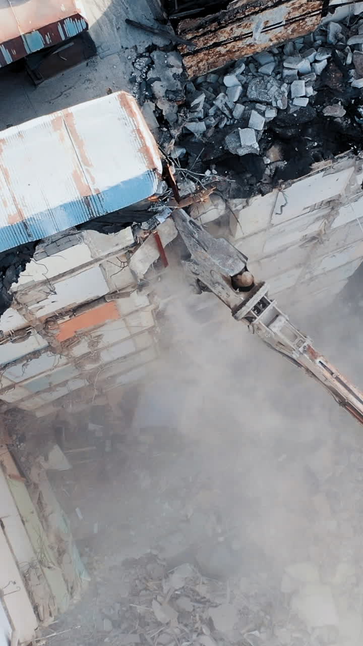 Dismantling of concrete structures with an excavator. Demolition of a multi-story building, for future development of residential buildings. Vertical video