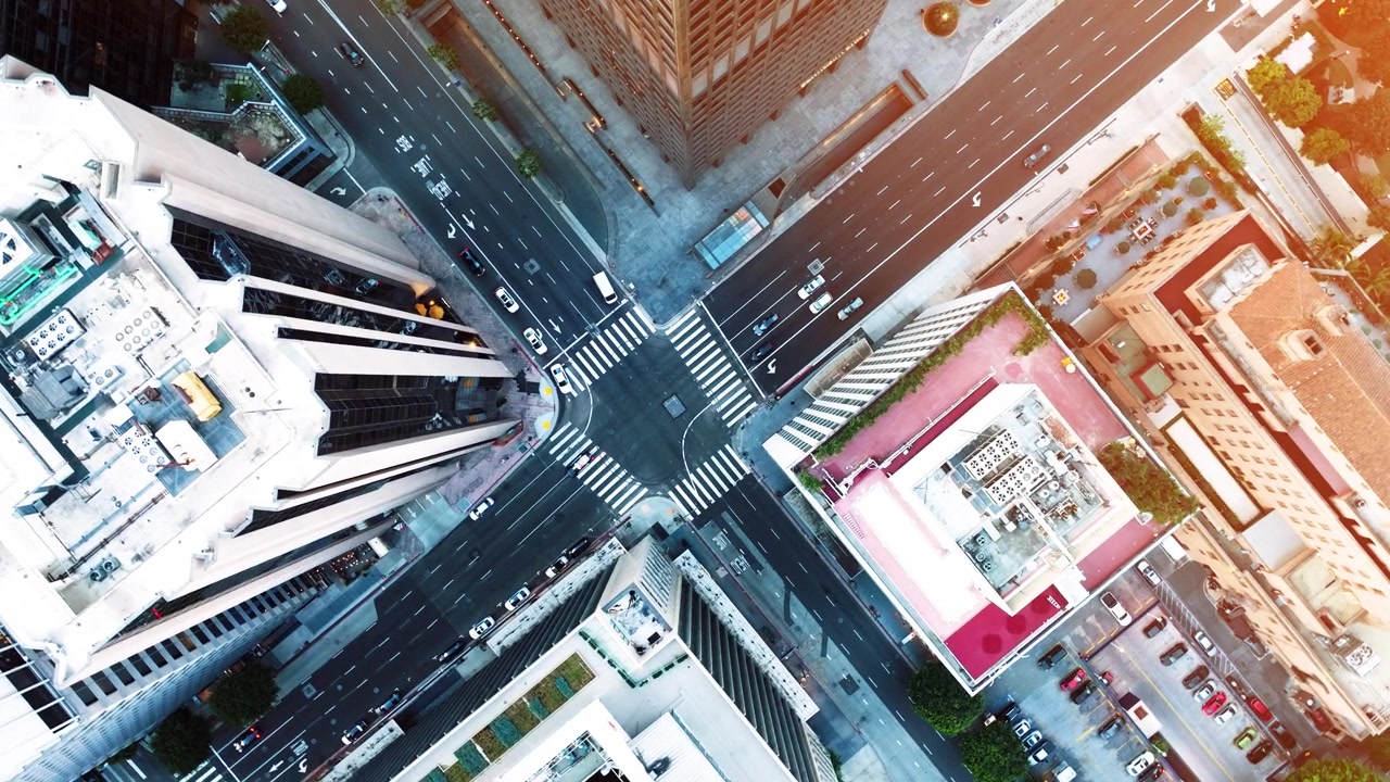 Varios ángulos muestran la infraestructura y la congestión del tráfico del centro de Los Ángeles durante la hora punta. Vehículos de cercanías navegan por las calles de la ciudad con un telón de fondo de rascacielos.