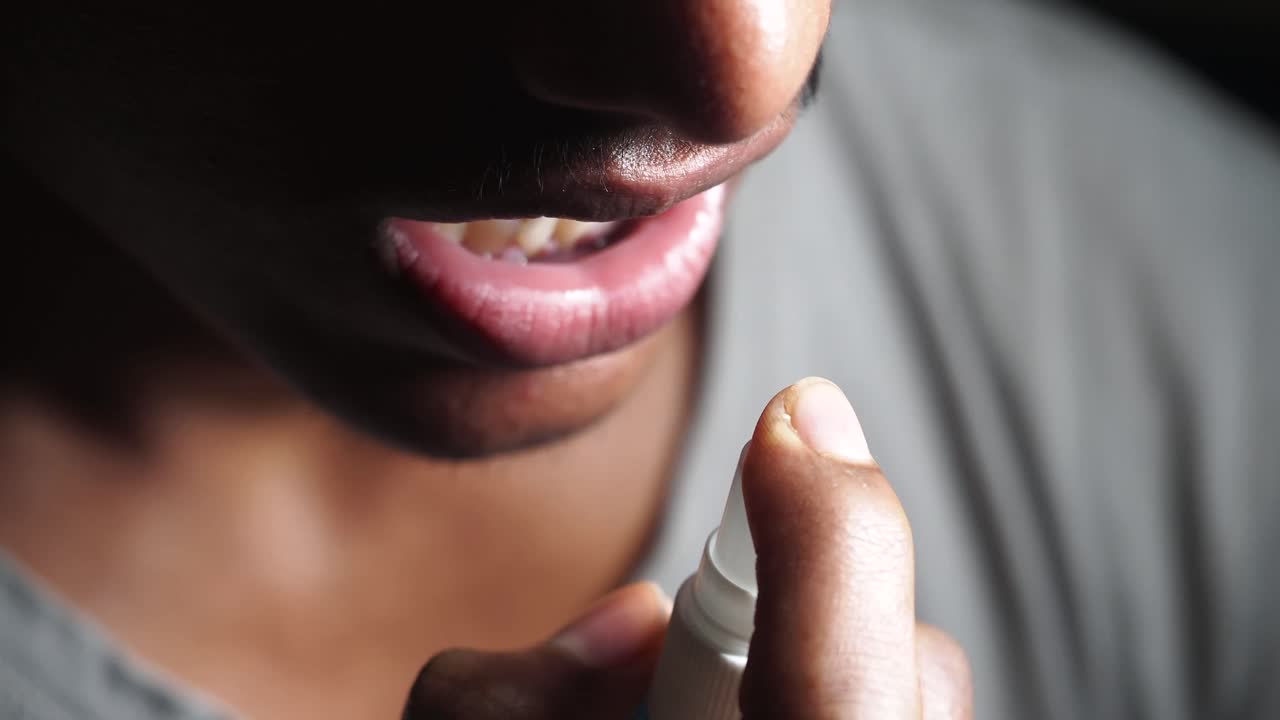 Close-up of a person using mouth spray