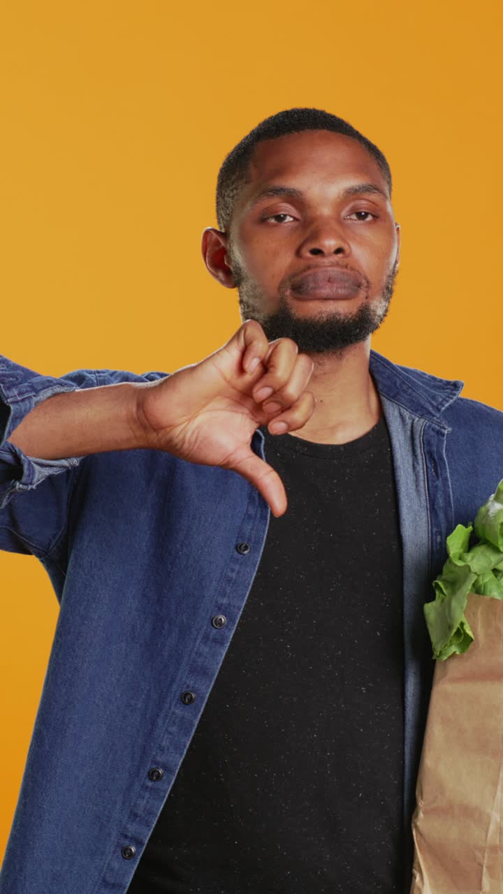 Uomo afroamericano che fa il gesto del pollice verso mentre tiene la spesa