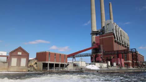 coal burning power plant with three smoke stacks panning to river dam