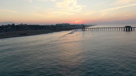 Eine-Atemberaubende-4K-Parallaxe,-Die-Bei-Sonnenaufgang-Den-Pier-In-Der-Surfstadt-Kalifornien,-USA,-Umkreist,-Während-Touristen-Und-Urlauber-Die-Aussicht-Genießen