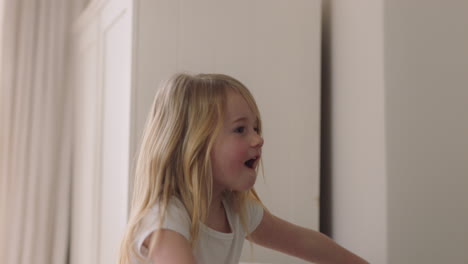 beautiful little girl jumping on sofa dancing having fun child in playful mood enjoying weekend morning at home