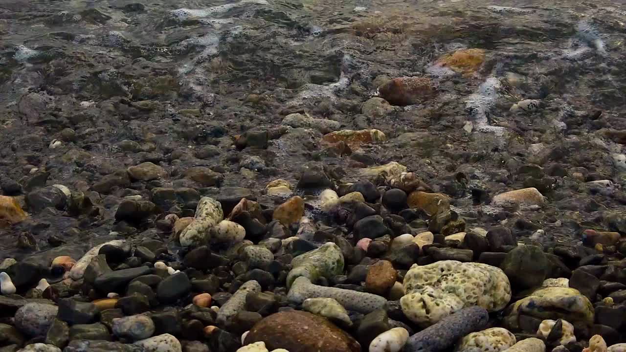 L'acqua si riversa sulle pietre della riva, schiumando lungo il percorso.