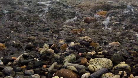 El-Agua-Se-Precipita-Sobre-Y-Sobre-Las-Piedras-De-La-Orilla,-Formando-Espuma-En-El-Camino