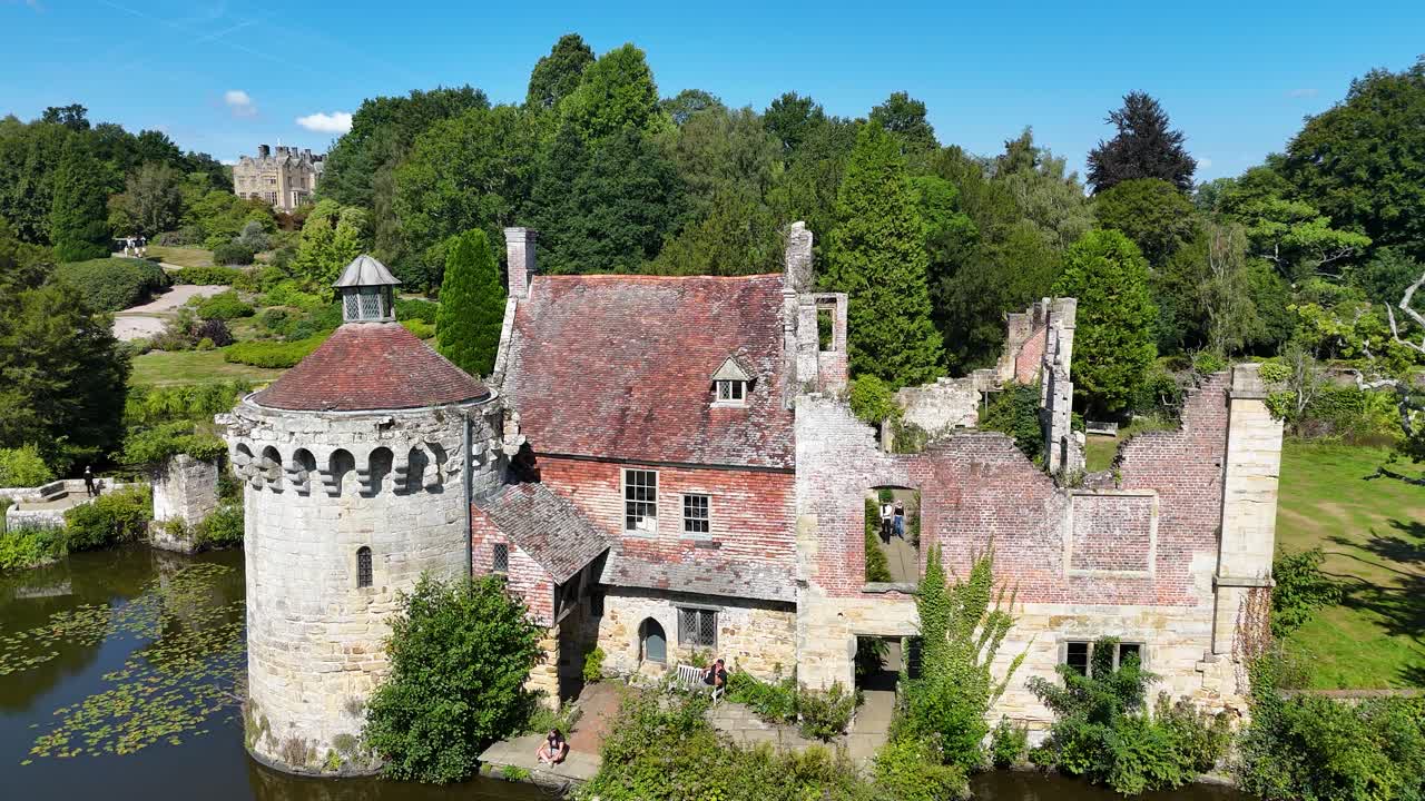 Naturskøn droneoptagelse af Scotney Castle, Kent, med fantastisk middelalderarkitektur i ruiner, fredfyldte voldgravsrefleksioner og frodigt engelsk landskab. Ideelle stockoptagelser til turisme- og kulturarvsfilm.