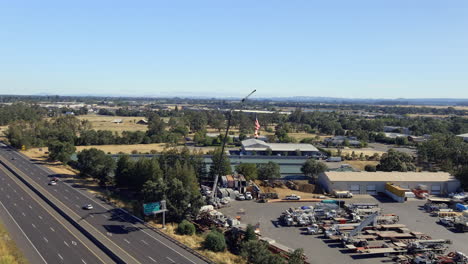 A-US-flag-on-a-crane-blowing-in-the-wind-showing-patriotism-on-an-American-holiday---aerial-orbiting-view