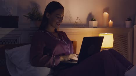 mujer usando la computadora portátil en la cama por la noche