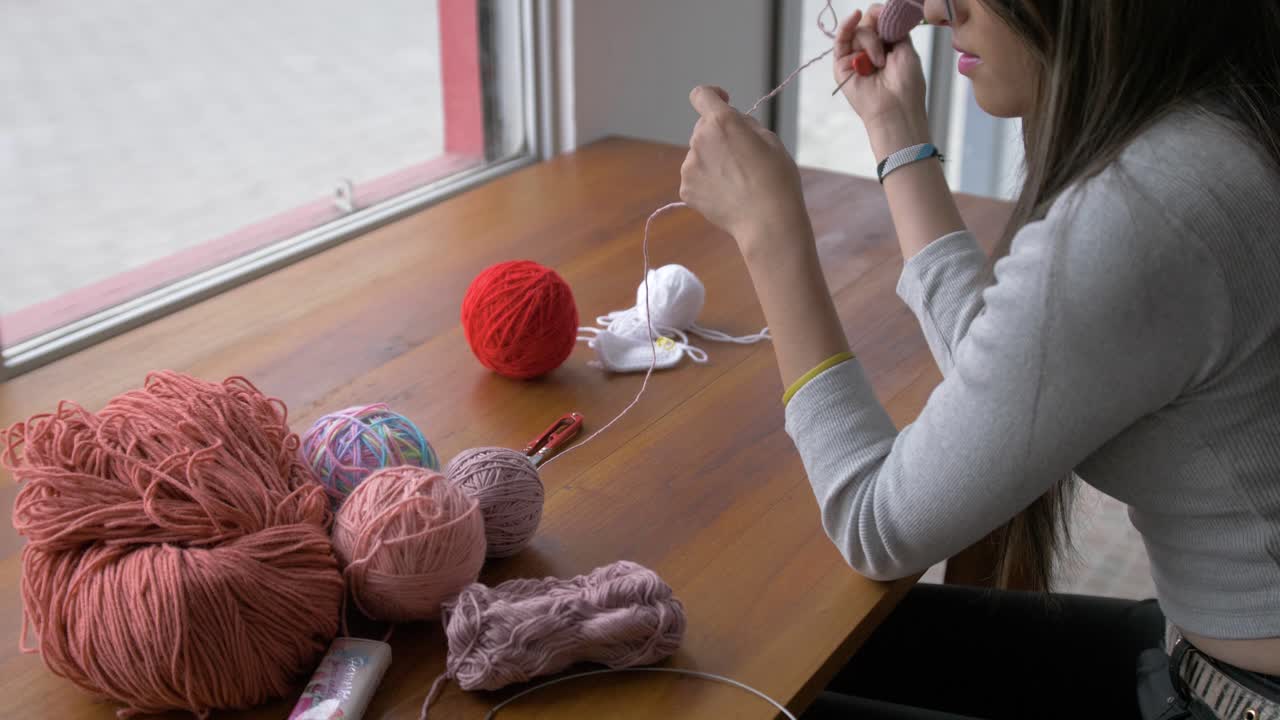 한 여인이 창문  ⁇ 에서  ⁇ 을  ⁇ 는 테이블에서  ⁇ 의 공을 조정합니다.