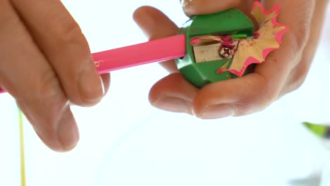 Close-Up-of-Hands-Sharpening-a-Pink-Pencil-with-Green-Sharpener