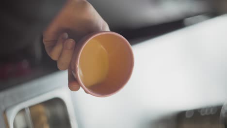 vertical, café recién tostado en taza se gira y se sostiene en la mano por encima del mostrador