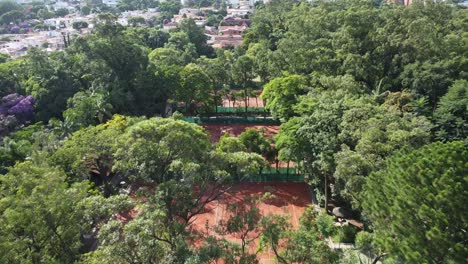 movimiento hacia adelante con drones filmando hermosas canchas de tenis en medio de árboles y mucha naturaleza, temprano en la mañana