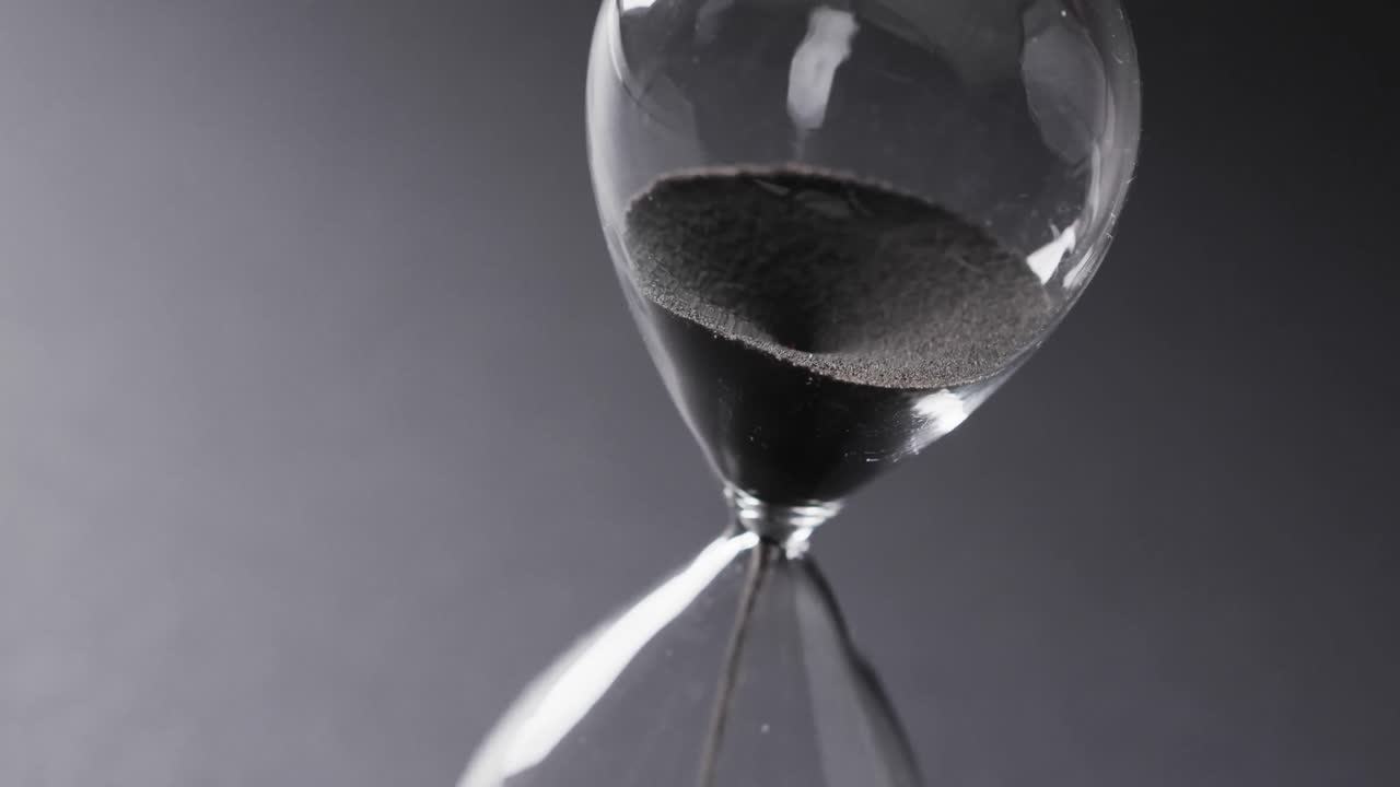 Video of hourglass with sand pouring, copy space on grey background