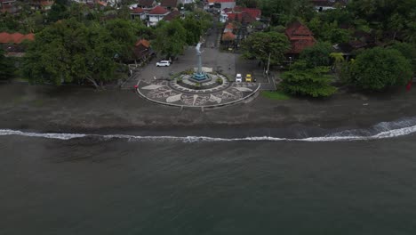 A-dolphin-statue-on-the-beach-in-Lovina,-Bali-on-a-rainy-day,-aerial