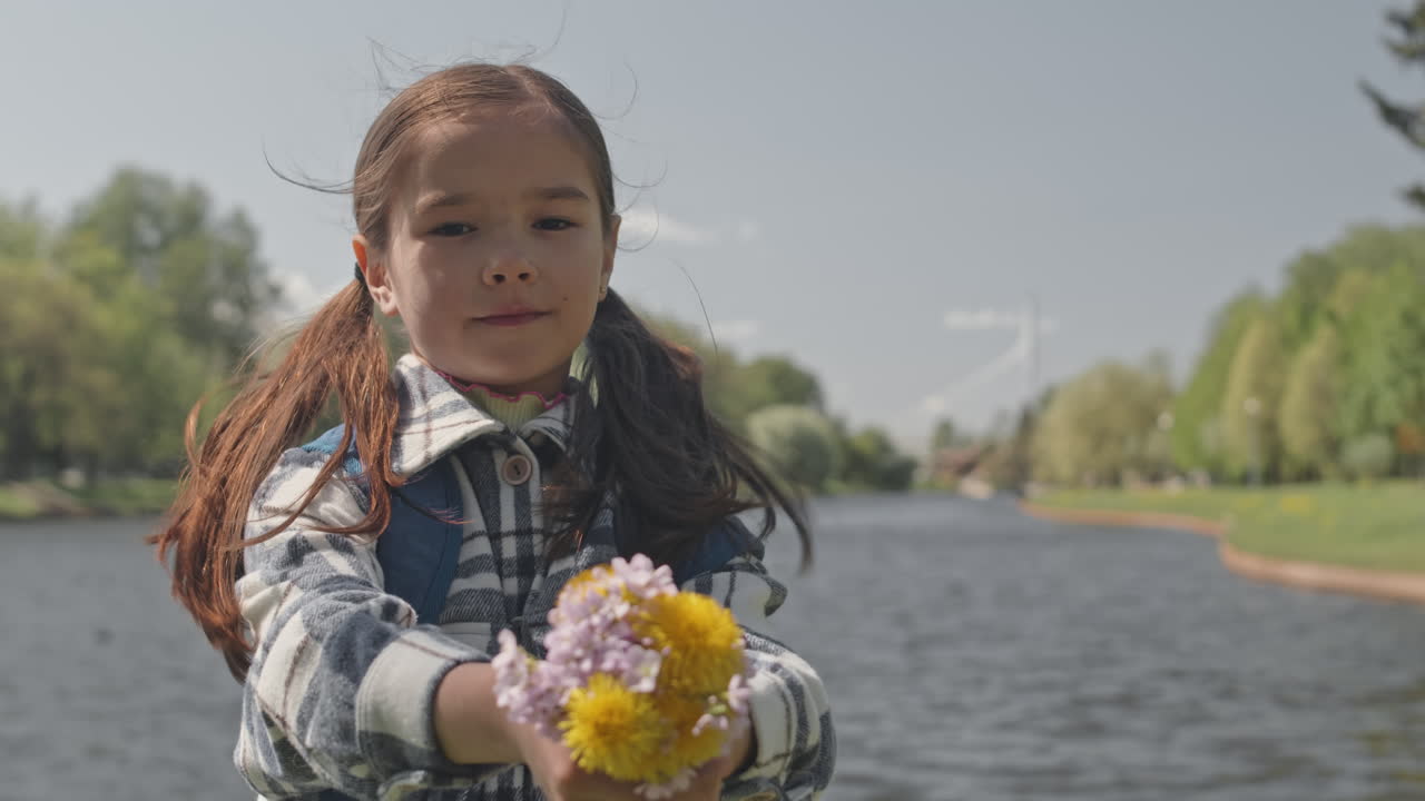 Girl holding flowers near a lake