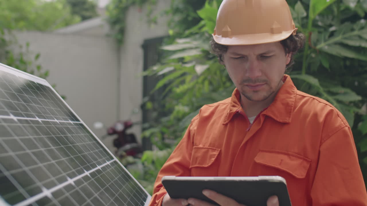 PV Installer Working on Tablet by Solar Panel