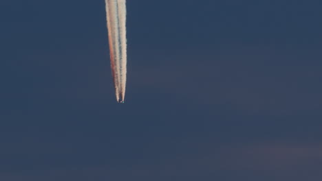 airplane with colorful contrail at dusk