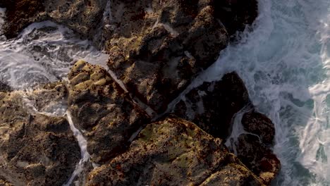aerial view of ocean waves crashing on rugged rocks