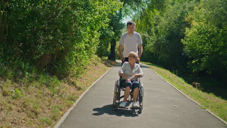 man pushing woman in wheelchair in a park