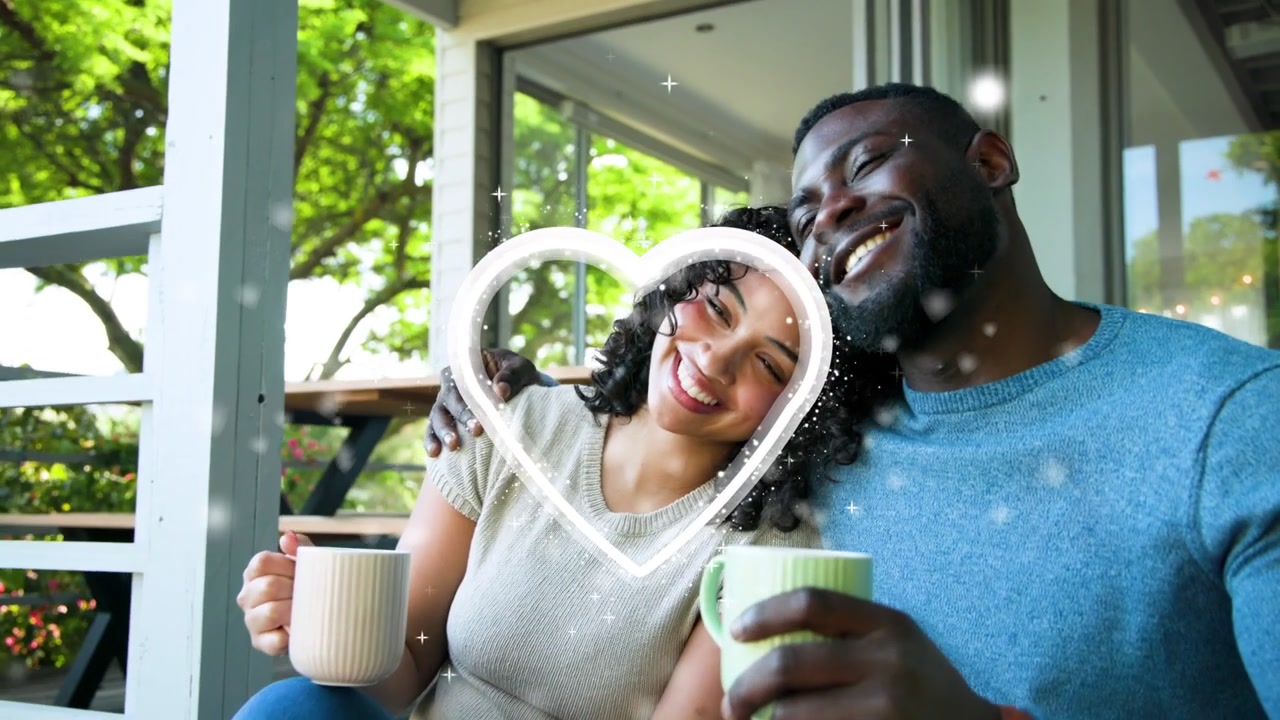 Uomo e donna seduti in veranda con tazze, che condividono un momento tranquillo con un'overlay a forma di cuore che si accende, che evoca uno stile di vita rilassato.